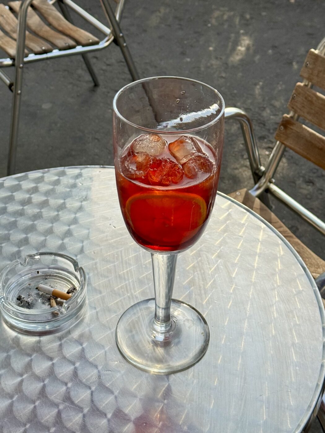 a metal table with a large glass of a negroni sbagliato on it