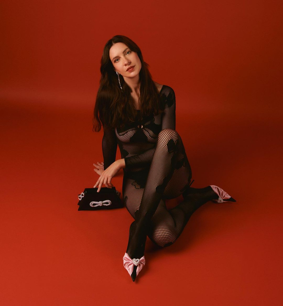 Popa, in a black mesh outfit on a red background