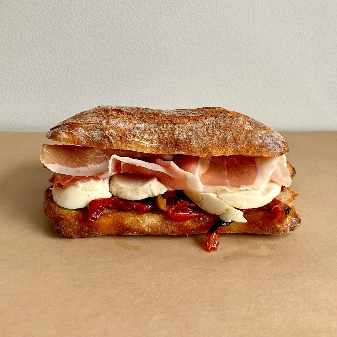 a ciabatta sandwich with prosciutto, mozzarella, and roasted red peppers