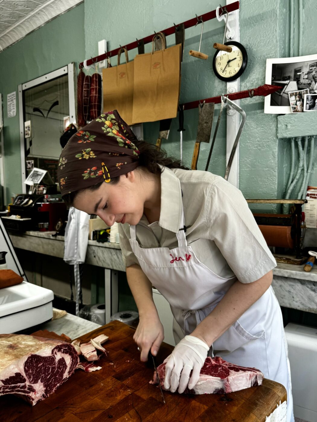 Jen Previoso behind the butcher counter slicing into a cut of beef at albanese meats & poultry