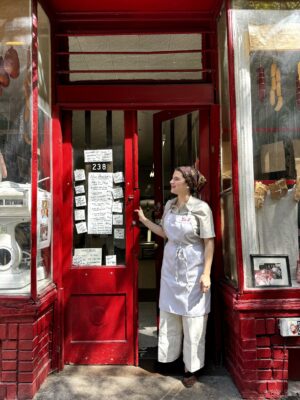 Jen Previoso standing out front the iconic red storefront of Albanese Meats & Poultry