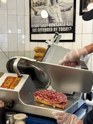 an image of someone slicing meat onto a sandwich at Faicco's Italian Deli