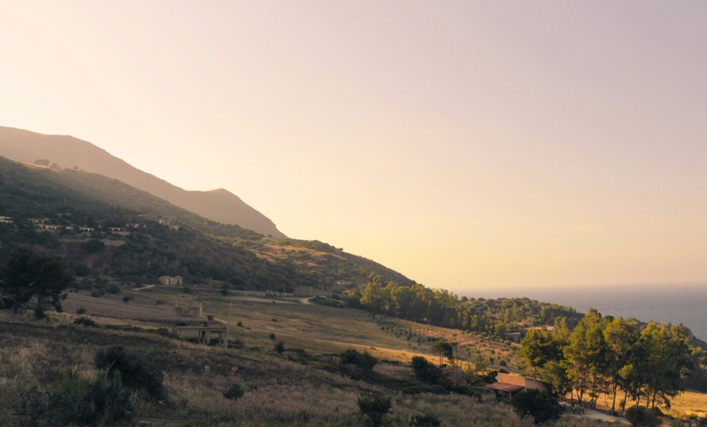 the hills of the west coast of sicily bathed in the orange light of dusk