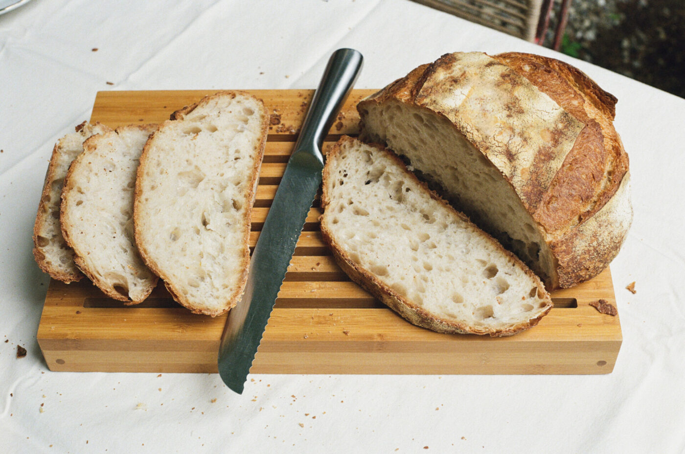 a bread board with a knife and a few slices cut from a loaf