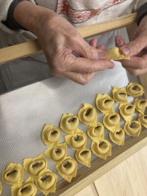 a old woman's hands pinching closed tortellini in modena