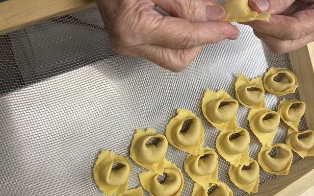 a old woman's hands pinching closed tortellini in modena
