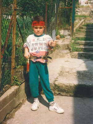 a vintage image of a young boy in a bandana holding a knife