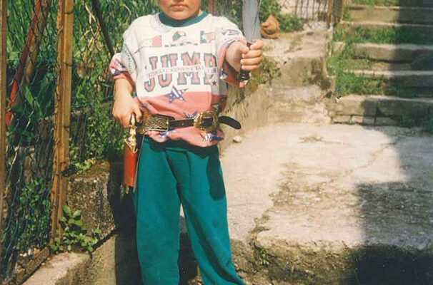 a vintage image of a young boy in a bandana holding a knife