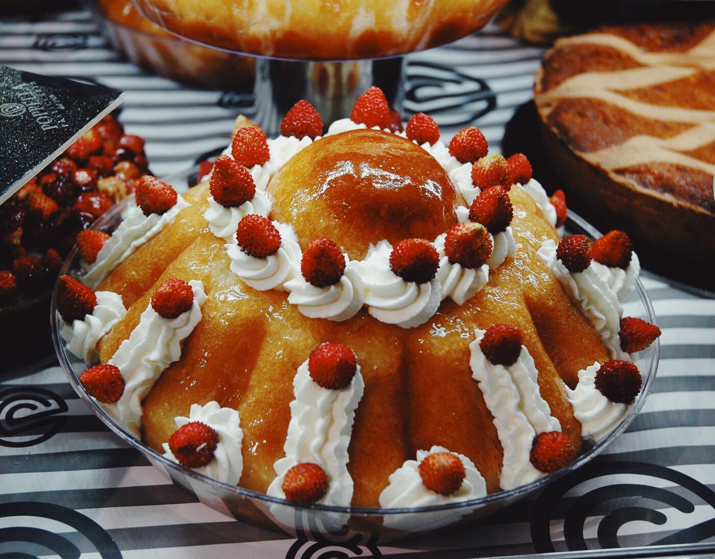 an oversized baba with whipped cream and raspberries in a bakery in naples