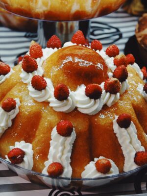 an oversized baba with whipped cream and raspberries in a bakery in naples