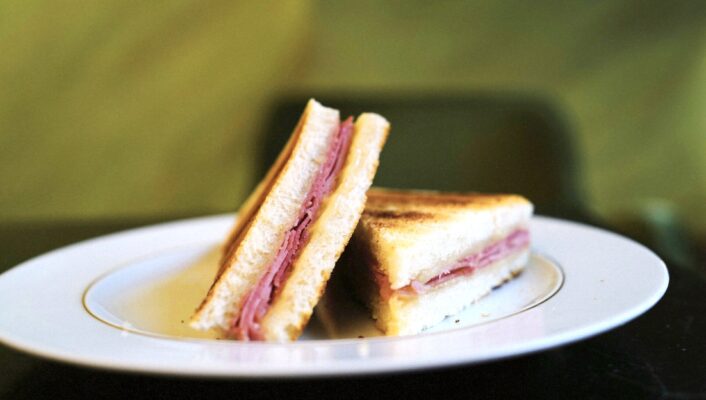 a perfect toast with ham and cheese sliced into triangles on a plate