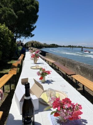 a long table set up along the water on an island by venice