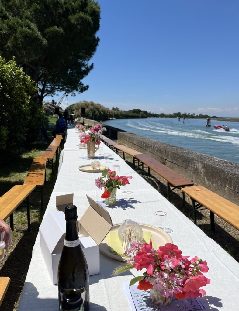 a long table set up along the water on an island by venice