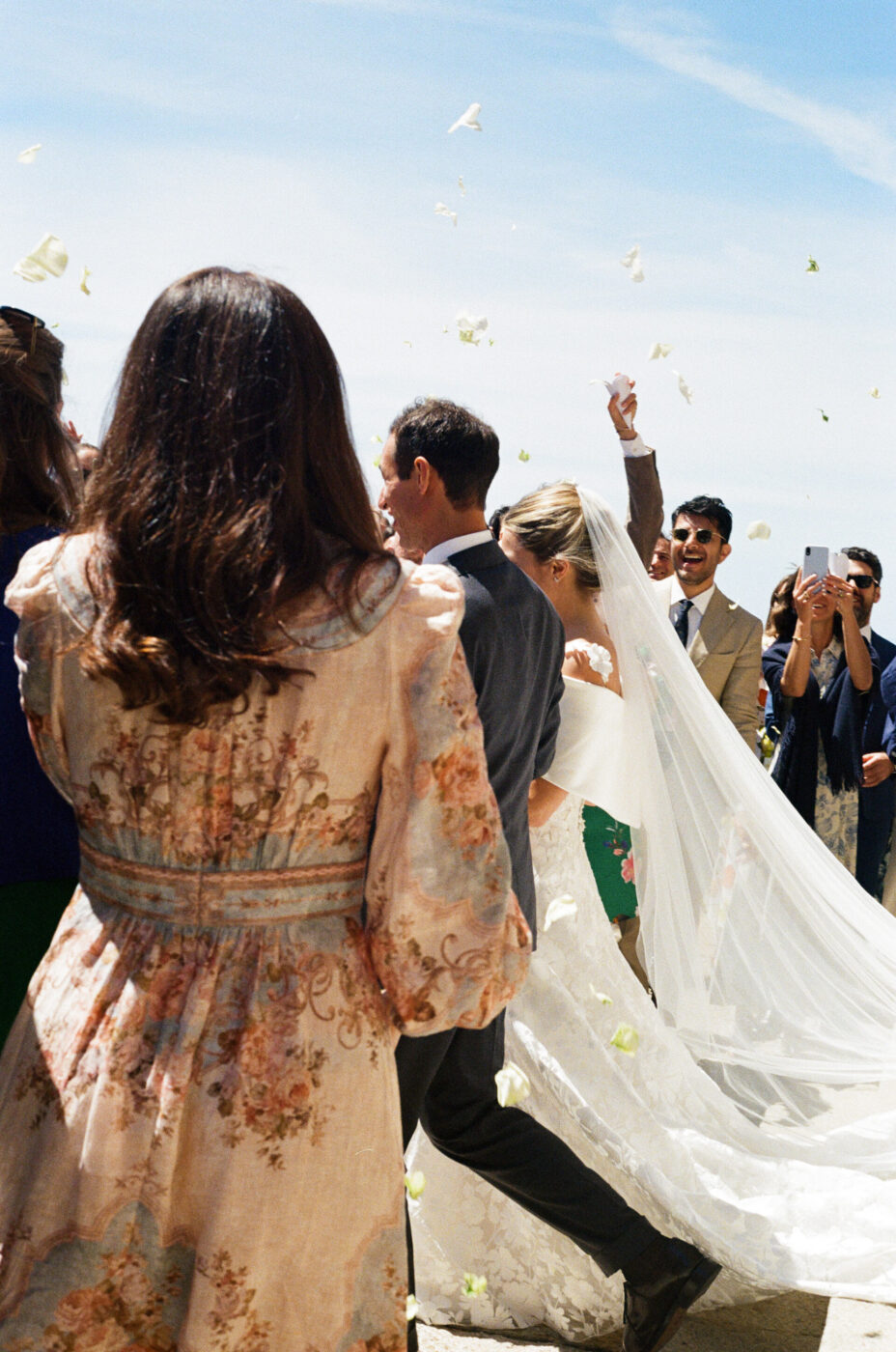 a bride and groom walking away from the church and flower petals thrown at them