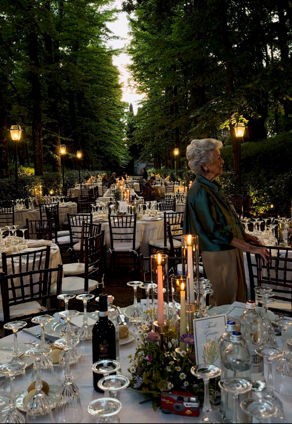 a bunch of round tables set up between the cypress trees at Agriturismo I Bonsi for a wedding reception
