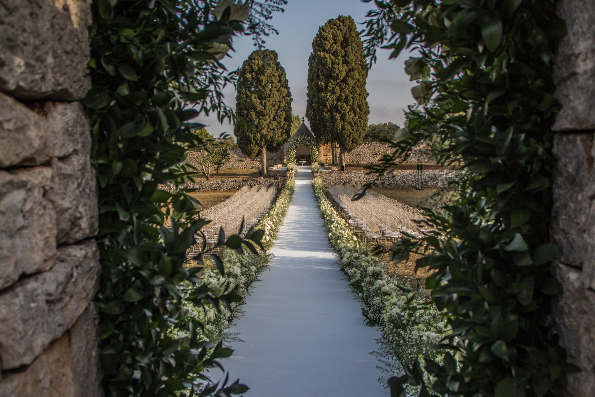the aisle leading to a beautiful altar in a trulo lined with flowers at masseria lamacoppa