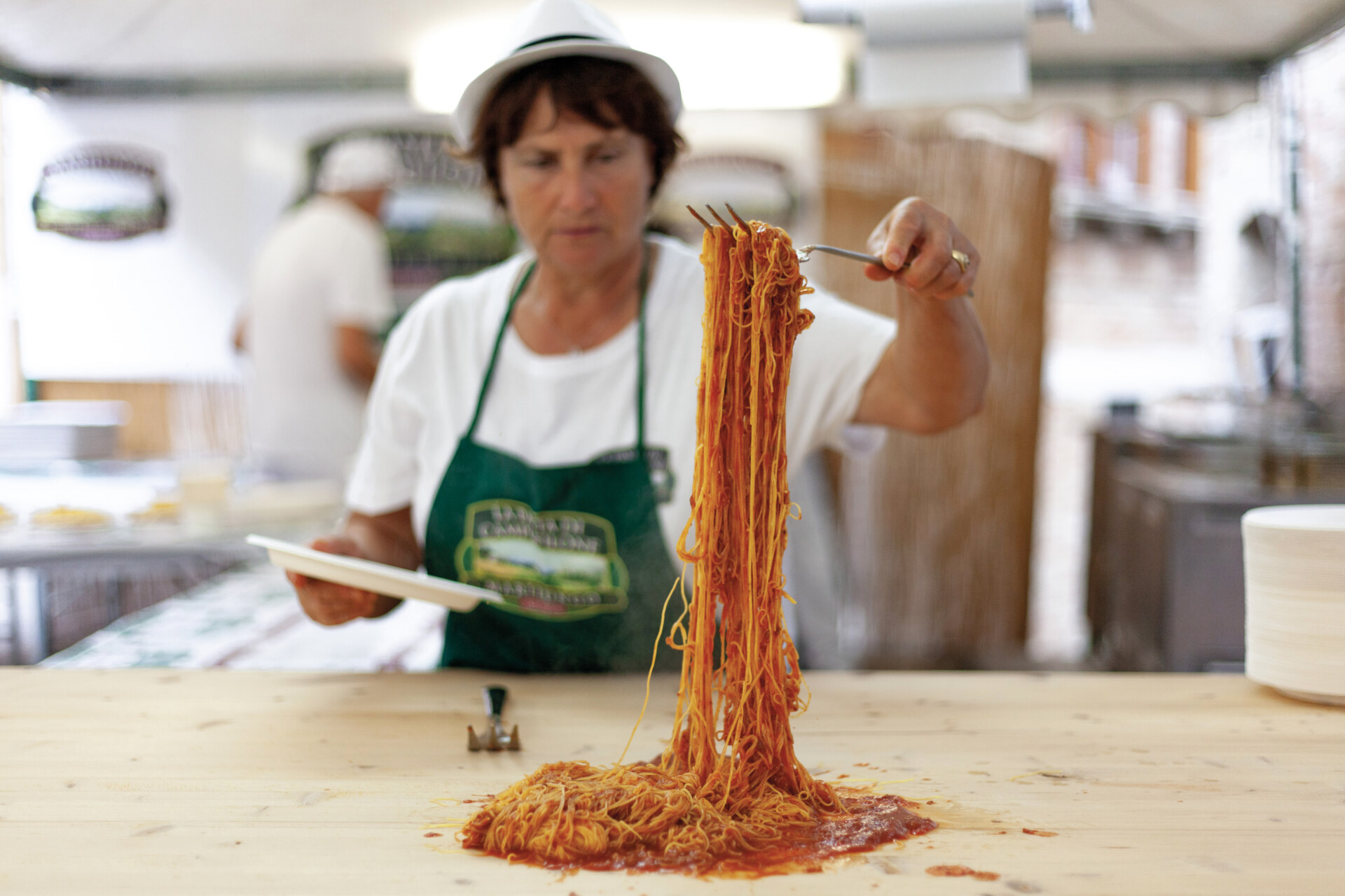a woman forking a giant forkful of spaghetti at the Sagra dei maccheroncini di Campofilone