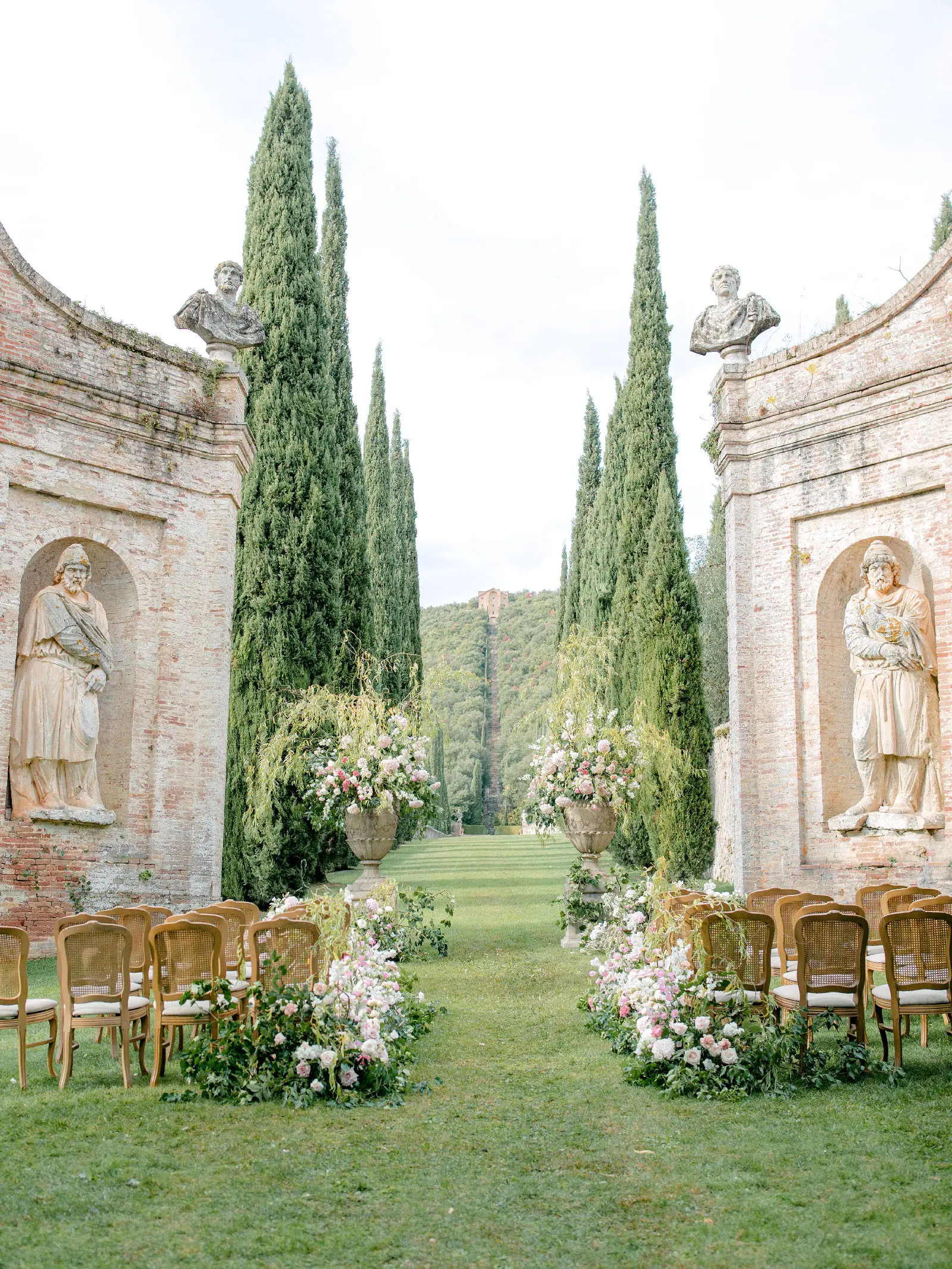 the wedding set up at Villa Cetinale with chairs and flowers creating an aisle that looks towards the hermitage