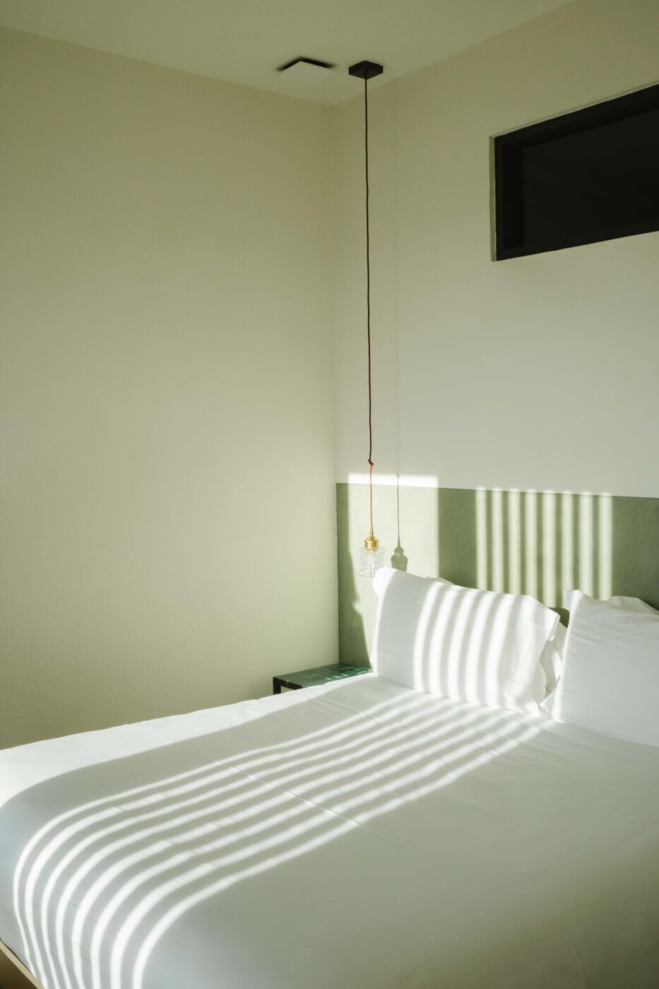 a white linen bed with stripes from the window shades at Dai Gresy