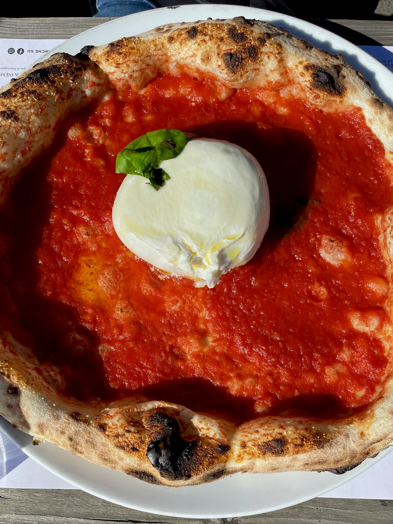 a pizza with red sauce and a circle of mozzarella in the center from bre