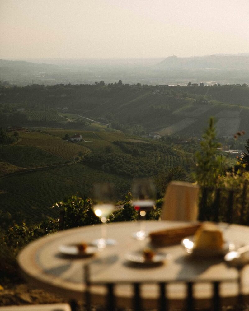 a beautiful table set with wine overlooking the piedmontese hills at dai gresy