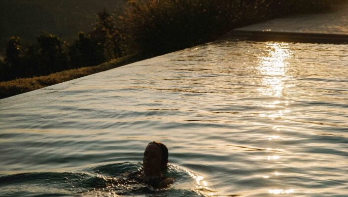 a woman swimming in the infinity pool at sunset at Dai Gresy