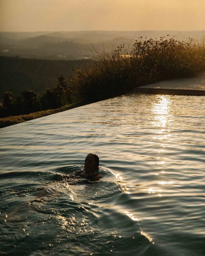 a woman swimming in the infinity pool at sunset at Dai Gresy