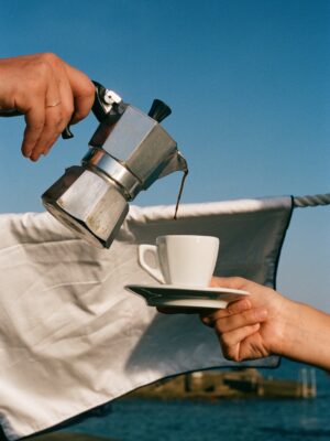 someone pouring a moka into a small espresso cup