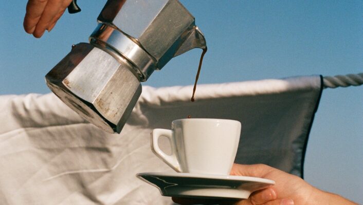 someone pouring a moka into a small espresso cup