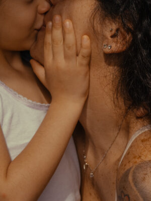 a mom kissing her young daughter, photographed by Lisa Sorgini