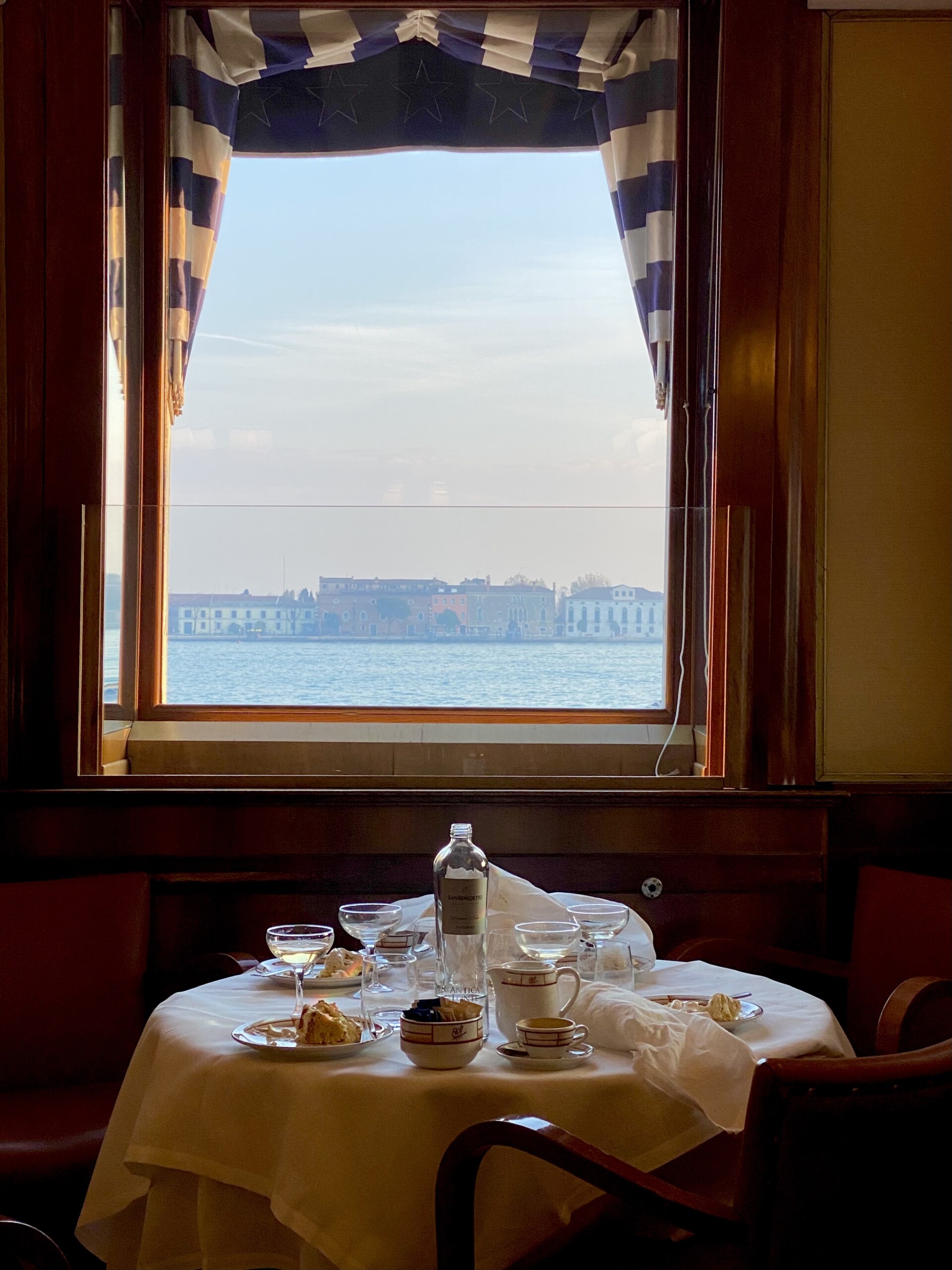 The pristine linen tablecloths of Harry's Bar with a view of the lagoon out the window