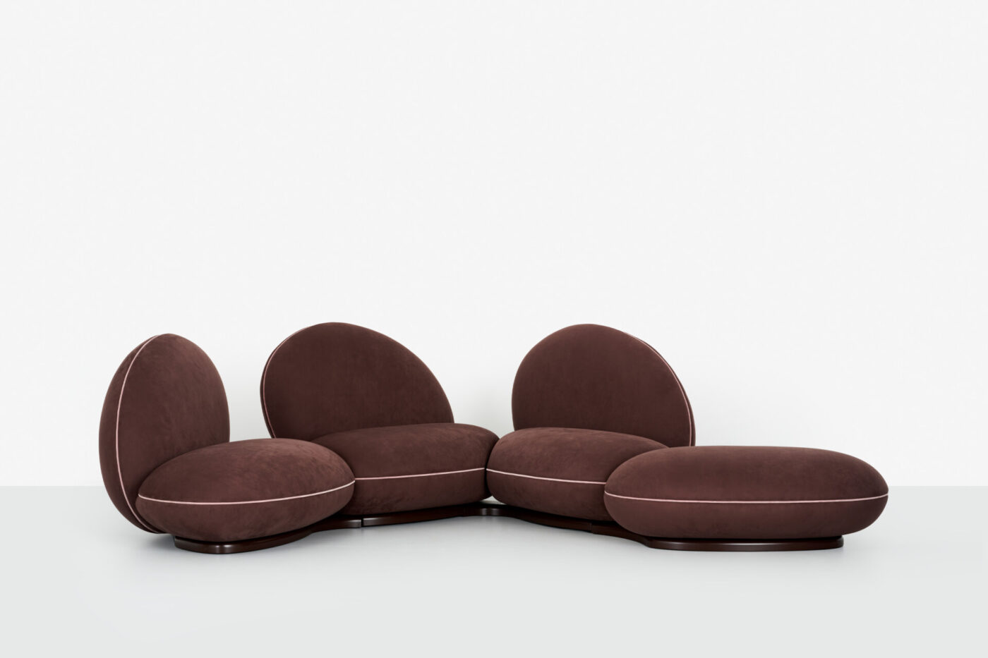 Modular Sectional Sofa - A modular sectional sofa with round, plush brown cushions and light piping, arranged in an open semicircle. The seating has no visible legs, set against a plain white backdrop.