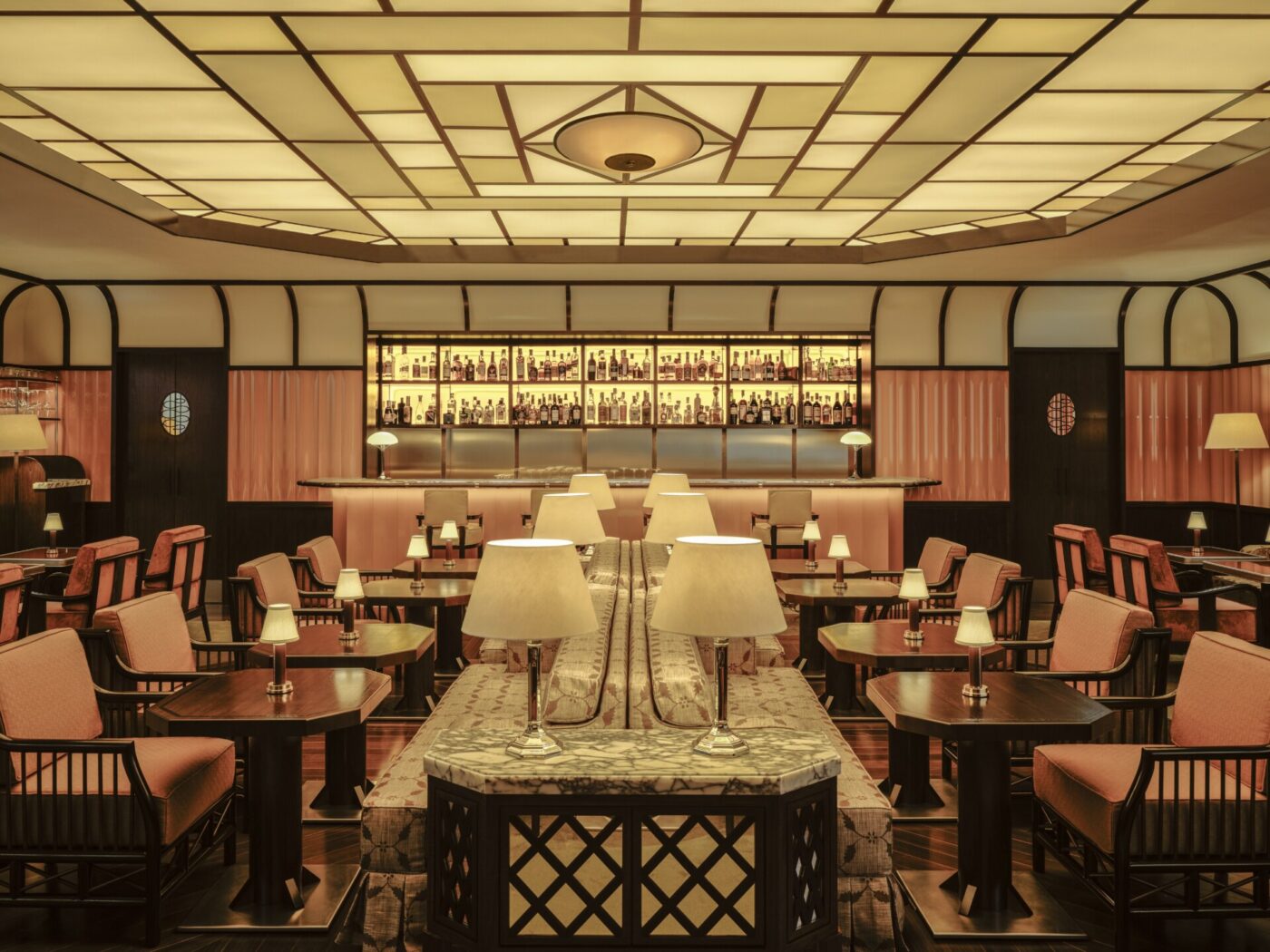 Elegante interno del ristorante" - Elegante interno del ristorante con un caldo e moderno design art déco. Illuminazione soffusa, tavoli ordinatamente disposti con sedie beige e lampade bianche. Un bar ben fornito e illuminato sul retro sotto un motivo geometrico sul soffitto esalta l'atmosfera sofisticata.