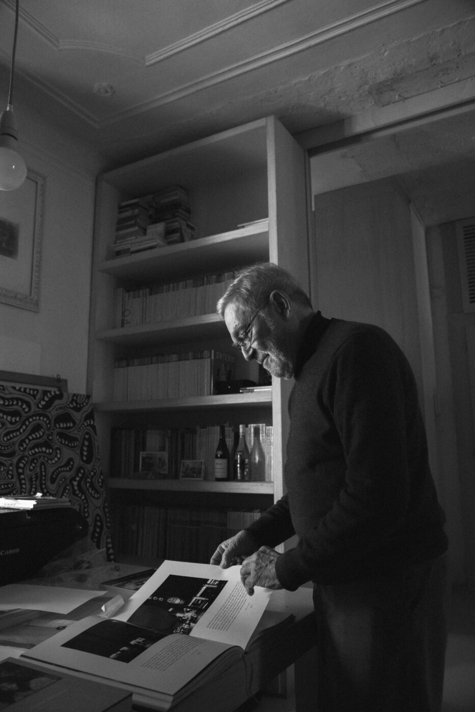 Santi Caleca looking over a book in his studio