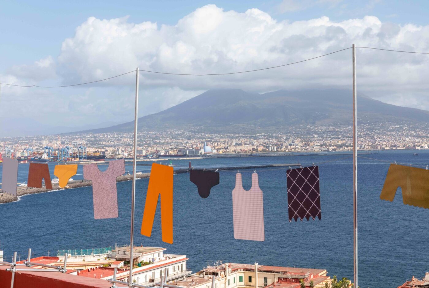 [Scenic Laundry Day] - Clothes hanging on a line with a scenic view of a bay and distant mountains. The garments sway gently, with a cityscape and fluffy clouds in the background under a clear blue sky.