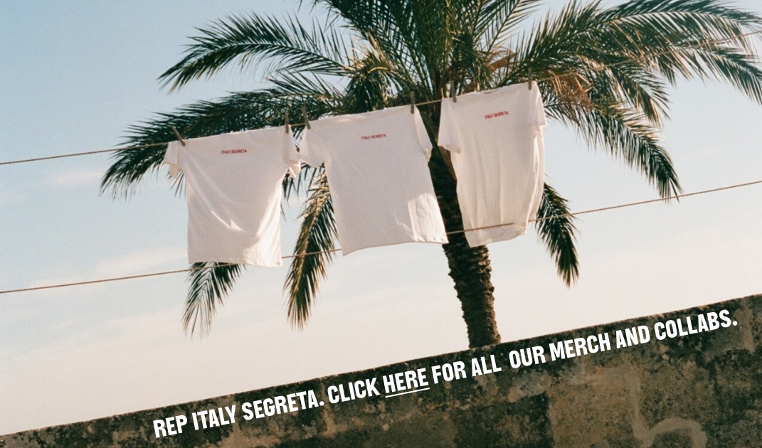 REP ITALY SEGRETA - Due magliette bianche sono appese a uno stendibiancheria davanti a una palma e al cielo azzurro. In basso si legge: "REP ITALY SEGRETA. CLICCA QUI PER TUTTO IL NOSTRO MERCHANDISE E LE NOSTRE COLLABORAZIONI".