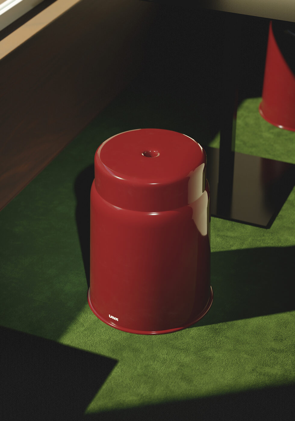 Ettore Stool by Gio Tirotto - A red stool stands upside down on a green carpet, casting distinct shadows in the sunlight. The scene is well-lit, with the sunlight creating high contrast between the surface and shadows.