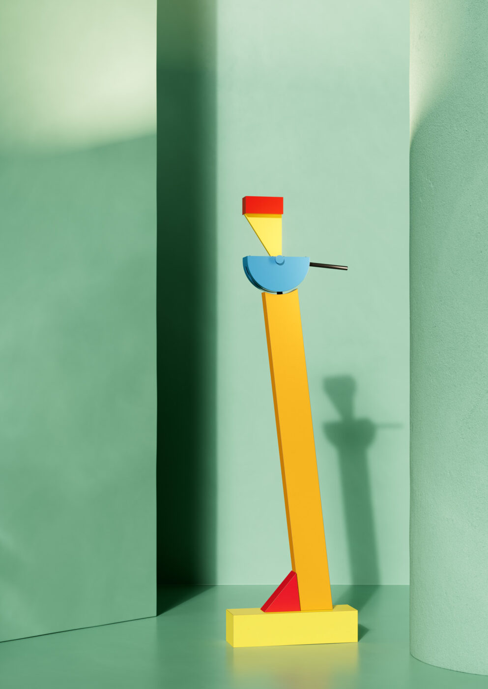 [Titolo dell'immagine] - Un'alta scultura geometrica astratta con un corpo giallo, una cima rossa e un semicerchio blu, che ricorda un uccello. Si erge su uno sfondo verde chiaro con pareti curve, proiettando un'ombra.