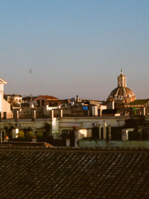 A cityscape at sunset - A cityscape at sunset shows historic buildings with domes and rooftops bathed in golden light under a clear blue sky.