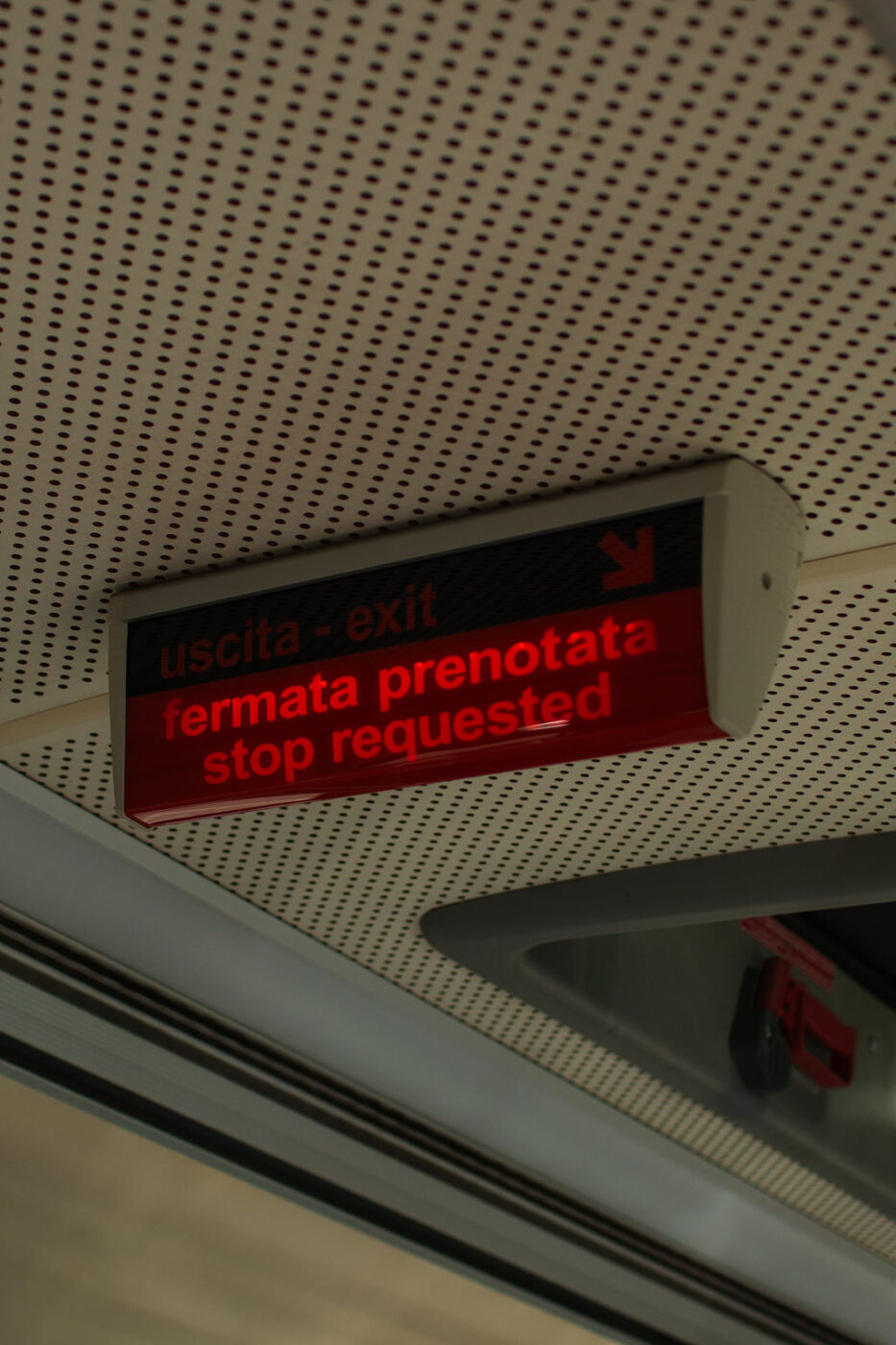 Uscita - exit / fermata prenotata - stop requested - A digital sign inside a vehicle displays “uscita - exit” and “fermata prenotata - stop requested” in red letters, indicating a passenger has requested the next stop.