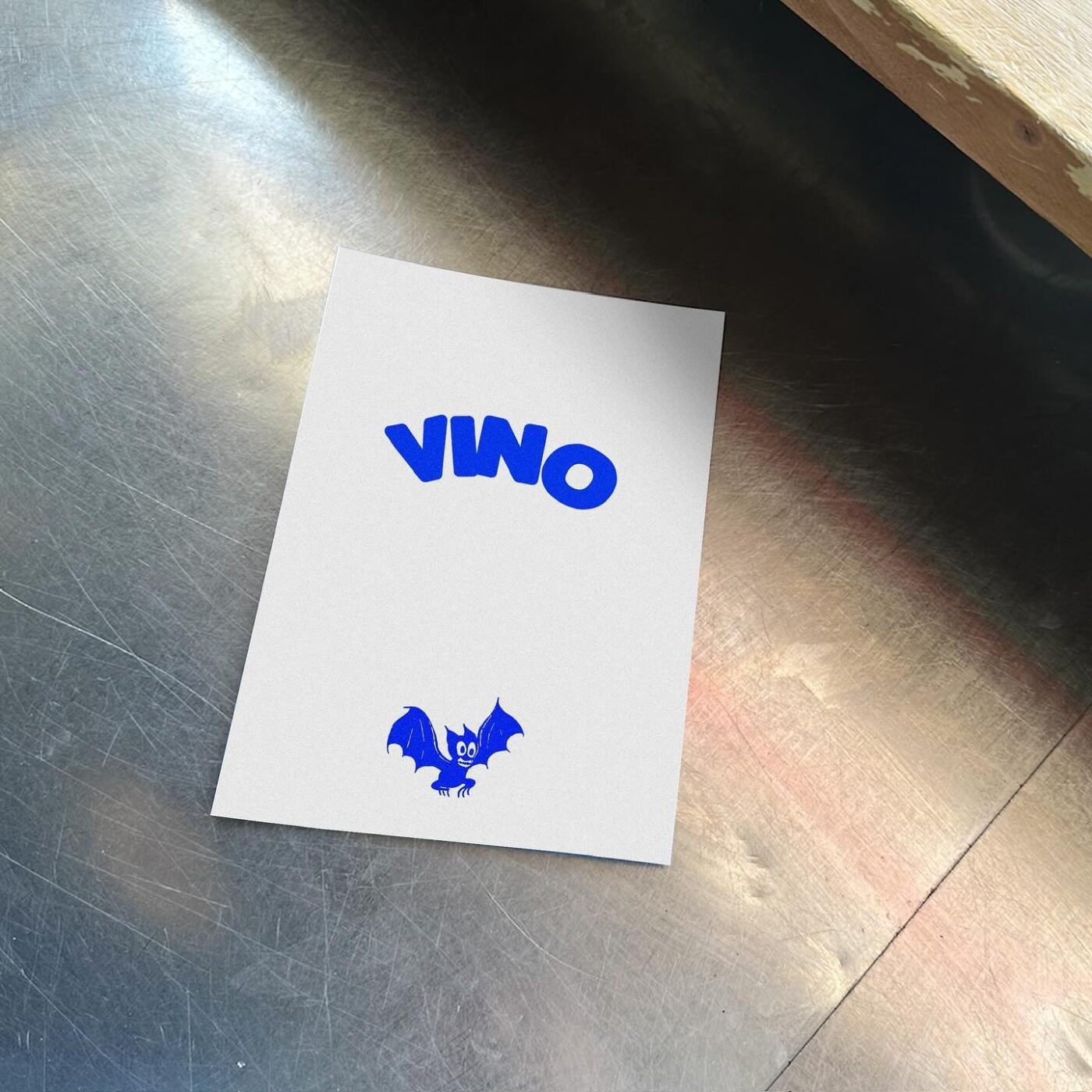 VIVO Card - A white card on a metallic surface displays the word VIVO in bold blue letters and a cartoon blue bat illustration near the bottom.