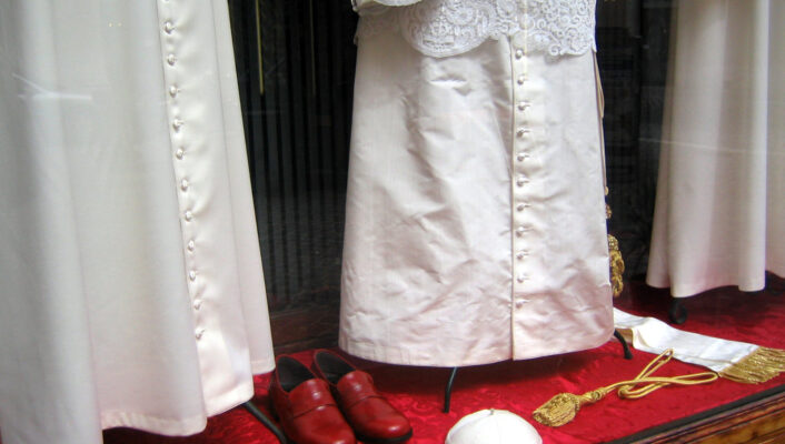 It looks like youre requesting alt text with a specific format based on the presence of an image title. Since the image title in your instruction isnt explicitly provided, Ill assume you want me to form an alt text that starts with [Image Title] -  if an image title is present. If the image title is, for example, Papal Vestments, then the alt text would be: Papal Vestments - A display case shows white clerical garments with pearl buttons, a lace overlay, a white skullcap, a gold cord, and a pair of red shoes on a red velvet surface. If you have a different or specific image title youd like to use, please provide it and I can generate the exact formatted alt text!.