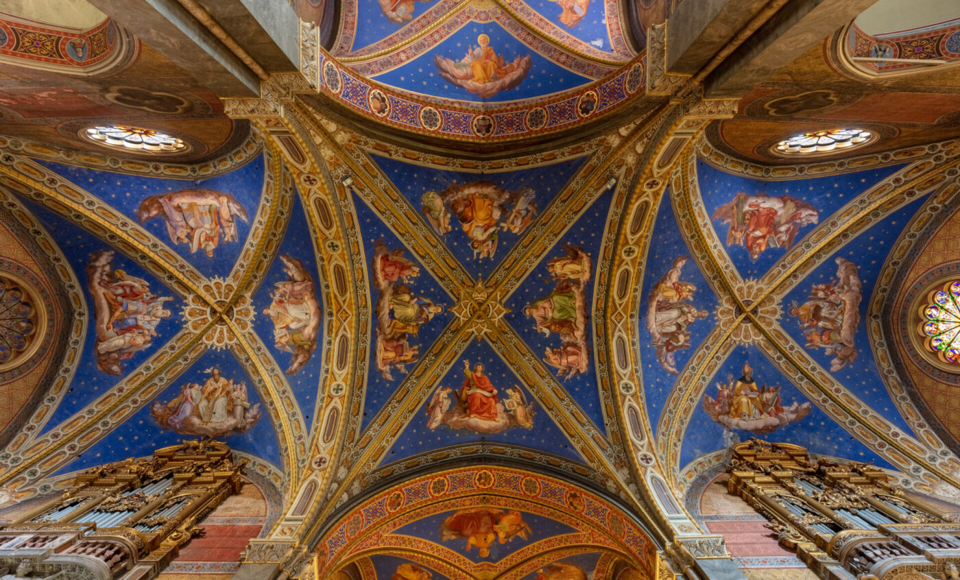 Soffitto decorato della cattedrale con dettagli blu e oro, caratterizzato da elaborati affreschi religiosi, angeli e santi circondati da stelle e archi decorativi, visti dal basso.