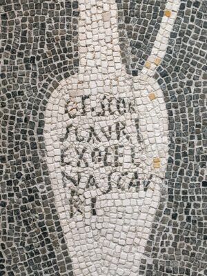 A black and white mosaic of a tall, narrow-necked jug with a handle. The jug is outlined in white tiles, with Latin text inside, all set against a background of small dark tiles. Since no image title was provided, the alt text reads as given. If you provide an image title next time, Ill prepend it accordingly!.