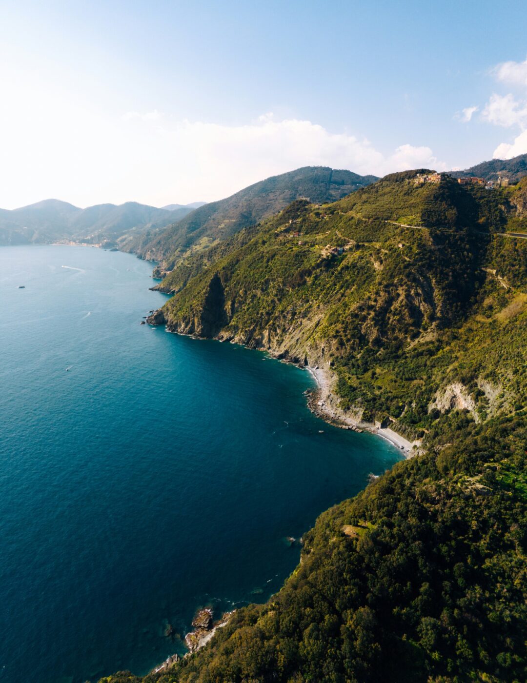 Vista aerea di una costa frastagliata con ripide colline verdeggianti che incontrano il mare blu intenso sotto un cielo limpido. Piccole insenature e scogliere costeggiano l'acqua e il paesaggio si estende a perdita d'occhio. *Se fornisci il titolo dell'immagine, lo includerò all'inizio secondo le tue istruzioni.*.