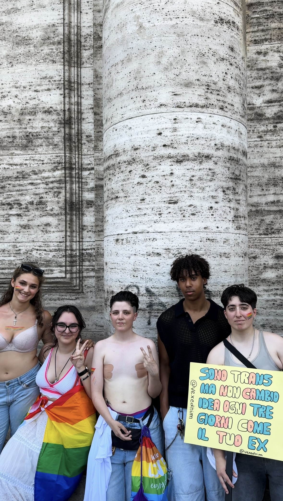 La descrizione dell'immagine non riporta un titolo esplicito. Se l'immagine avesse un titolo (ad esempio, "Pride Celebration 2024"), il formato sarebbe: Pride Celebration 2024 - Cinque persone sono in piedi sorridenti davanti a un muro di pietra. Una tiene un cartello in italiano e un'altra si tiene sulle spalle una bandiera arcobaleno. Sembrano partecipare a un evento pride, indossando abiti casual e di genere diverso. Se non c'è un titolo dell'immagine, utilizzare semplicemente il testo alt come scritto: Cinque persone sono in piedi sorridenti davanti a un muro di pietra. Una tiene un cartello in italiano e un'altra si tiene sulle spalle una bandiera arcobaleno. Sembrano partecipare a un evento pride, indossando un abbigliamento casual e di genere diverso. Se mi fornisci un titolo esplicito dell'immagine, posso formattarla di conseguenza!.