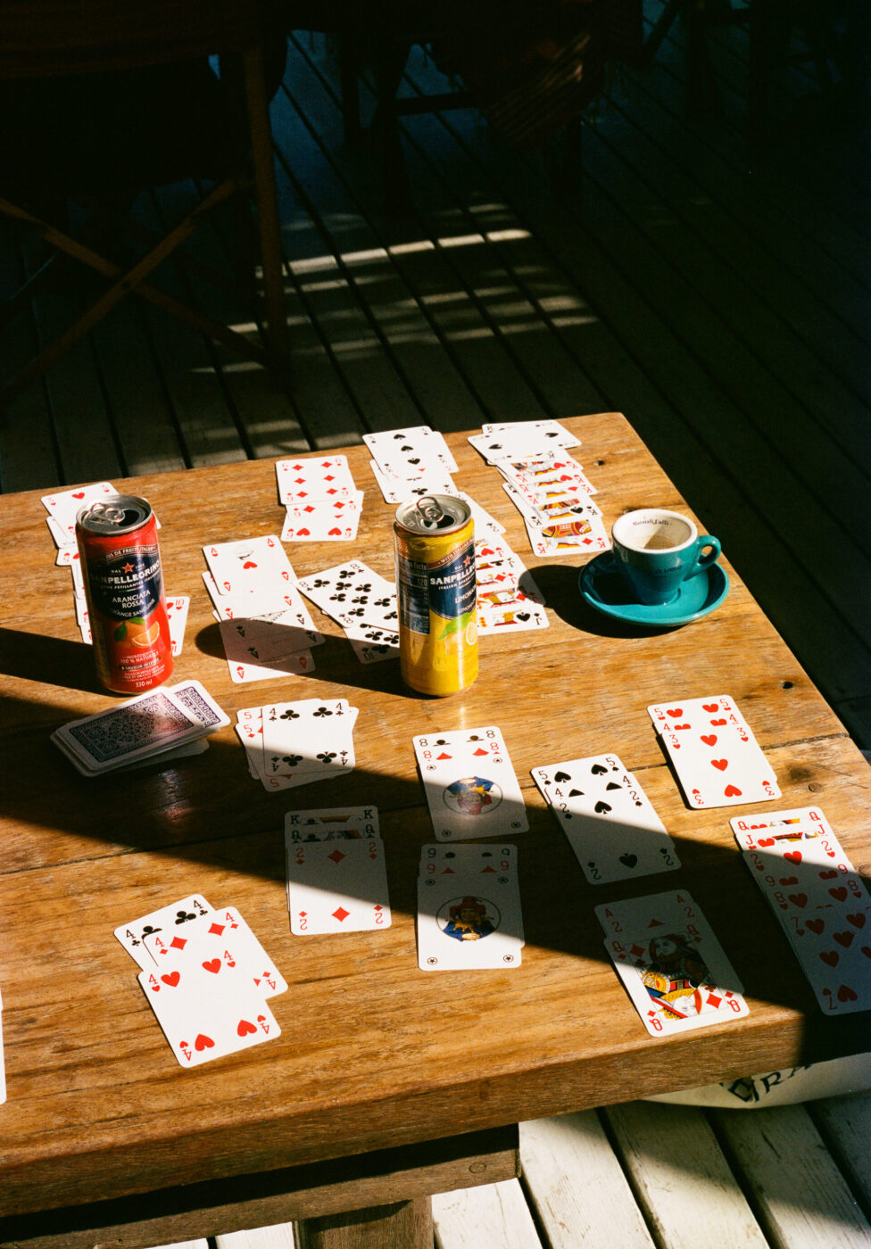 Non è stato fornito il titolo dell'immagine. Se il titolo dell'immagine è, ad esempio, "Game Night Setup", ecco come dovrebbe essere formattato il testo alt: Game Night Setup - Un tavolo di legno con carte da gioco sparse, due lattine di energy drink, un mazzo di carte e una tazza di caffè verde acqua con piattino. La luce del sole e le ombre creano un'atmosfera calda e rilassata. Se non c'è un titolo dell'immagine (come nel vostro prompt), utilizzate il testo descrittivo alt così come l'avete scritto. Fatemi sapere se volete specificare un titolo per l'immagine!.