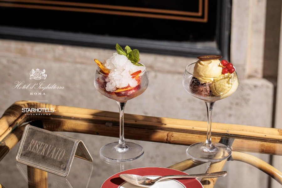 Two dessert glasses: one with peach ice, mint; one with gelato, chocolate curls, berries. Riservato sign and red plate nearby.