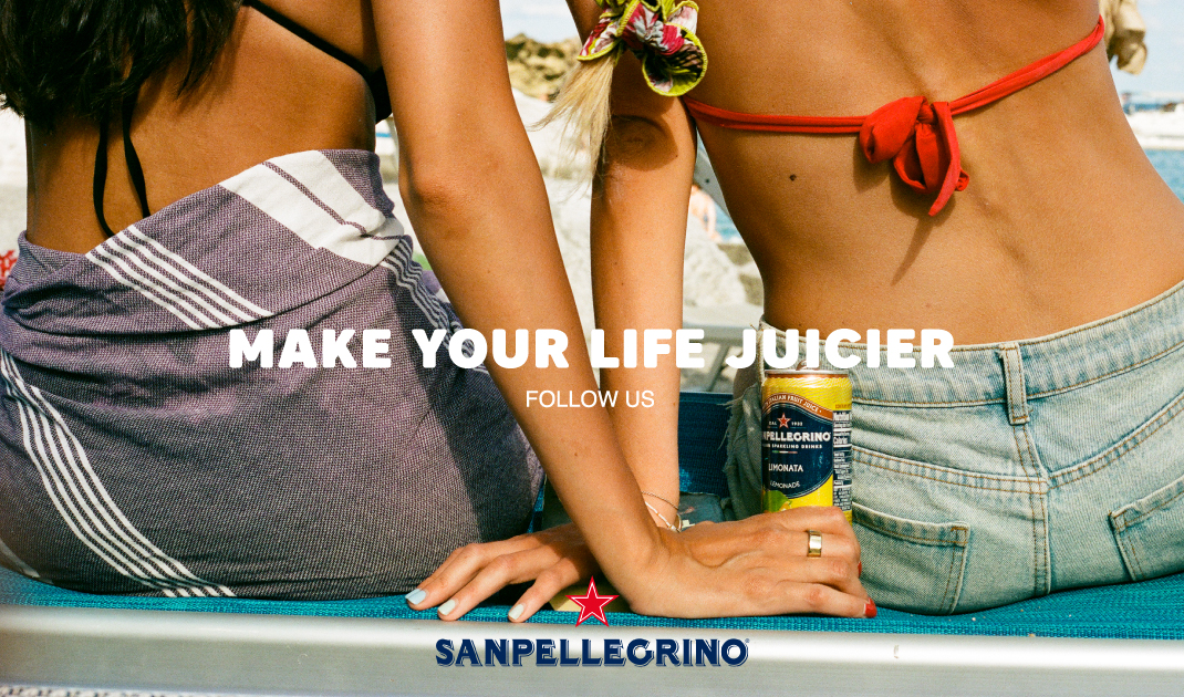 Due donne in costume da bagno siedono su una sedia a sdraio, una con in mano il Sanpellegrino. "RENDI LA TUA VITA PIÙ SUCCOSA. SEGUICI". Logo in basso.