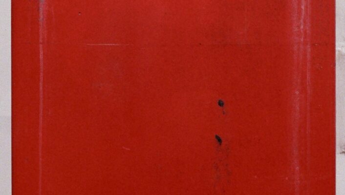 Primo piano di una cassetta postale rossa con l'etichetta POSTE in bianco, su uno sfondo semplice. La cassetta presenta segni di usura e di utilizzo.